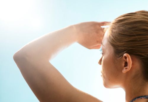 Woman shielding eyes from sun exposure